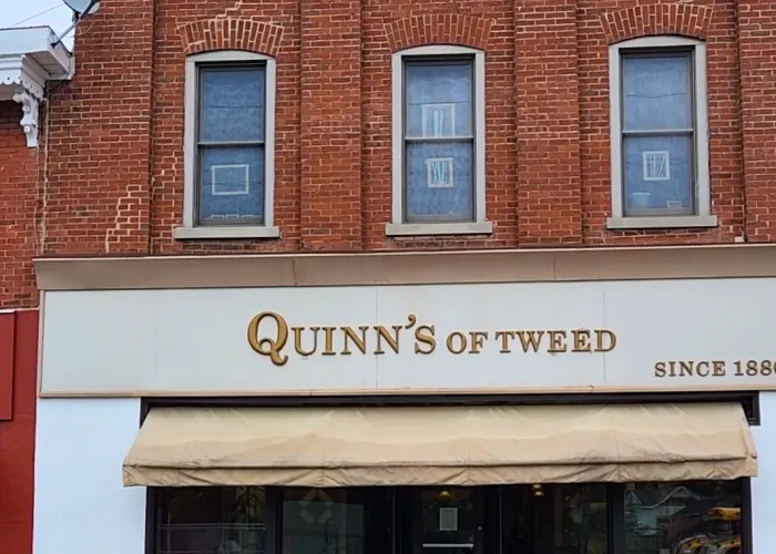Quinn's of Tweed Storefront. A large red brick building with gold lettering that reads Quinn's of Tweed